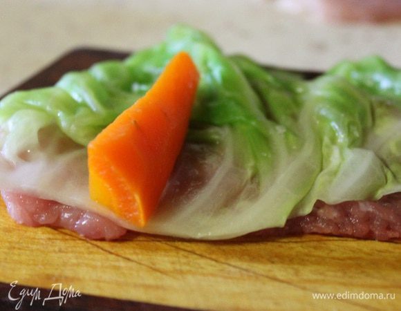 На отбитый кусочек свинины кладем лист капусты, на край капусты кладем брусок моркови..