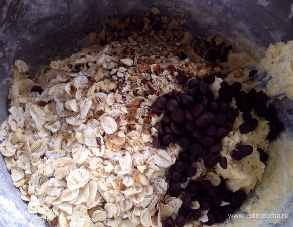 Затем всыпать овсяные хлопья, грецкие орехи и горсть шоколадных капель. Перемешать.