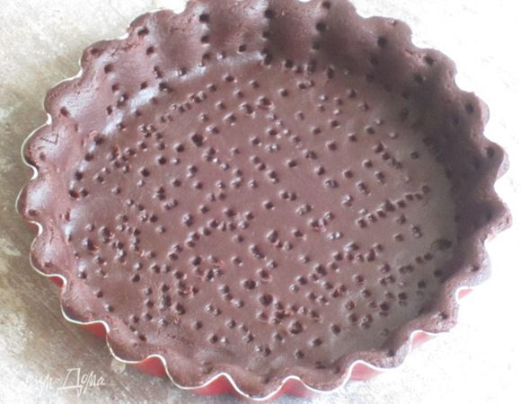 Наколоть тесто вилкой,положить пергамент и насыпать сухую фасоль. Выпекать в разогретой до 180 °С духовке 15 минут. Затем удалить пергамент с фасолью и выпекать ещё 5 минут. Остудить.