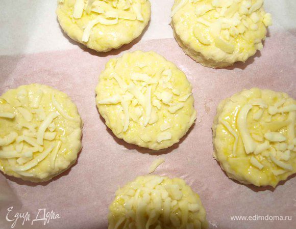 Смазываем сконы желтком и посыпаем сыром. Раскладываем на противне с интервалами друг от друга и отправляем в заранее разогретую до 220 градусов духовку. Выпекать 12-15 минут, пока сконы не поднимутся и не станут светло-золотистыми. 