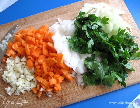 Оставшиеся лук, сельдерей и морковь мелко нарезать. Чеснок очистить, мелко порезать. К нарезанным овощам добавить листики петрушки.
