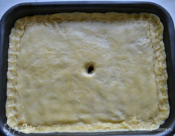 Из меньшей части теста раскатайте пласт для верха пирога. Накройте начинку тестом и защипните края. В центре сделайте небольшое отверстие для выхода пара.