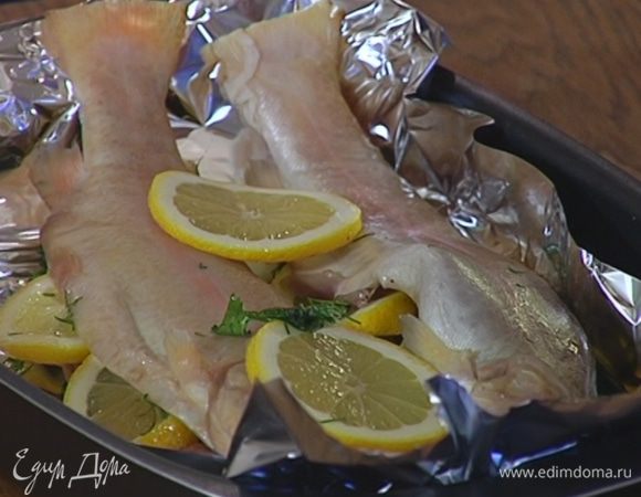 Небольшой глубокий противень выстелить фольгой, разложить оставшиеся веточки укропа и кружки лимона, а сверху поместить форель.