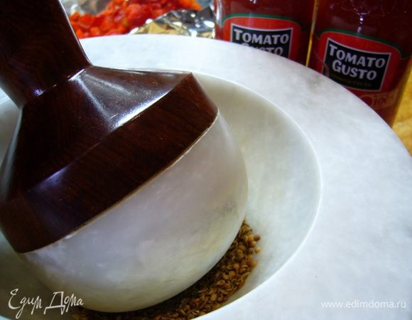 Перец чили освободить от плодоножки и семян, мелко нарезать.
В ступке растереть зиру и кориандр. Всыпать в сковороду вместе с перцем чили. Готовить 2 мин.
