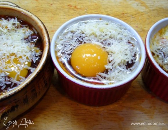 Керамические формочки смазать оливковым маслом, выложить томатно-фасолевый соус, сверху разбить яйцо, посыпать тертым сыром.
Отправить в духовку, разогретую до 200 град. на 12 мин.
