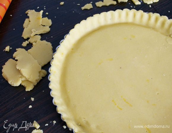 Тесто достать из холодильника, раскатать в пласт толщиной 0,5 см. С помощью скалки перенести тесто в форму, излишки обрезать. Наколоть тесто вилкой, накрыть бумагой и насыпать фасоль. Выпекать в разогретой духовке 25-30 минут (ориентироваться по своей духовке!) Готовый корж достать из духовки и остудить.