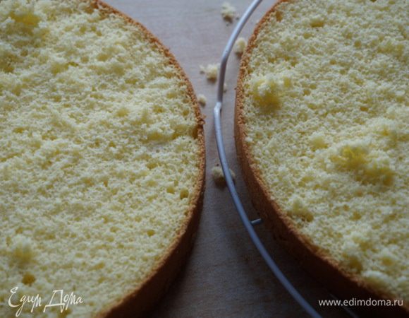 Вернемся к нашему бисквиту. Он уже давно остыл и немножко вылежался. Разрезаю его вдоль пополам. Ровненький, аккуратный, хорошо пропеченный (в разрезе), и, если бы он полежал еще с пол суток *отдыхая*, то и крошек бы не было в момент разрезания. Теперь кладем нижний бисквитный корж на блюдо, устанавливаем кольцо (бортик),выстилаем его кулинарной пленкой.