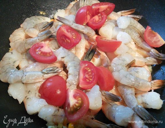 Добавьте помидорки, если они у вас крупные, порежьте их. Переверните креветки на другую сторону, влейте сок лимона и соевый соус. Всё вместе прогрейте, снимите с огня, посыпьте кинзой.