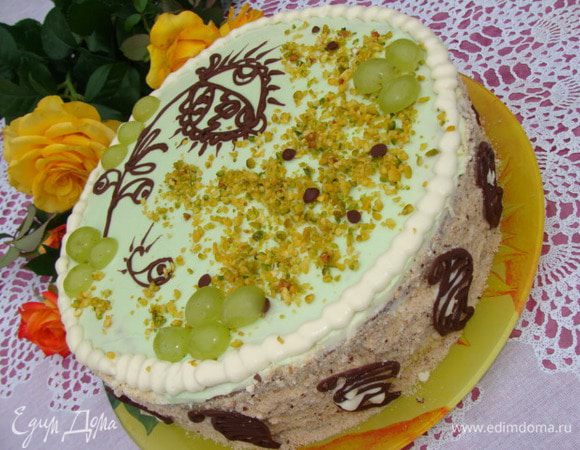 Обсыпать бисквитной крошкой, которая у меня была в запасе. А можно орехами или измельченным не ароматным печеньем. Верх торта я покрыла ганашем, смешанным с зеленым красителем. Украшения делала из качественного молочного шоколада, растопив его в микроволновке ( 1 минута мощность 750, достаем и перемешиваем). Поместила шоколад в корнетик, нарисовала узор на торте, остальное на плотном файле, затем отправила в морозилку на пару минут. Сбоку украшения крепила с помощью оставшегося ганаша.