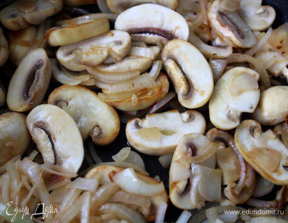 Лук и грибы нашинковать. Добавить в сковороду оставшееся масло и обжарить грибы с луком на среднем огне примерно 7-8 минут.