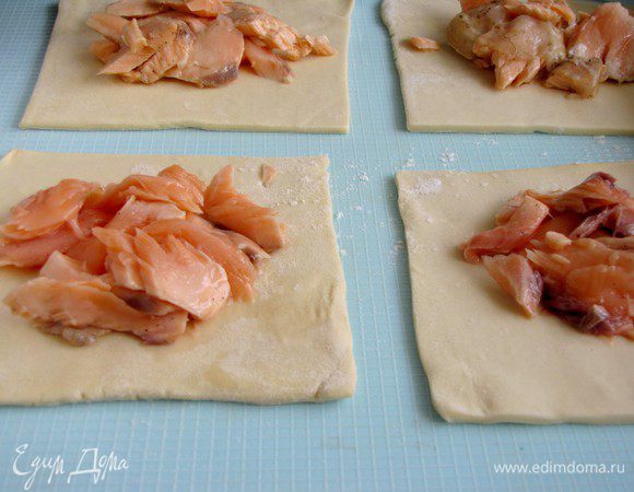 Форель остудить, разобрать на кусочки и выложить на квадраты теста.