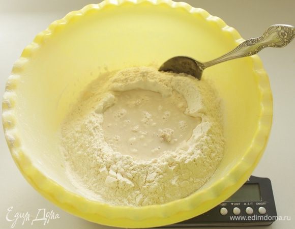 Насыпать муку в большую миску,сделать в ней углубление. Насыпать дрожжи,добавить к ним сахар и 70 мл теплой воды.