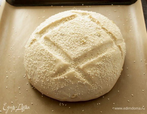 Нагреть духовку до 230 градусов.
Смазать хлеб водой, присыпать обильно кунжутом, сделать пару надрезов. 