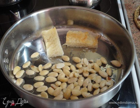 Чеснок почистить, нарезать мелко. На другой сковороде разогреть оставшееся масло, обжарить на нем до золотистой корочки миндаль, чеснок и 2 ломтика батона ( у меня белый хлеб). 