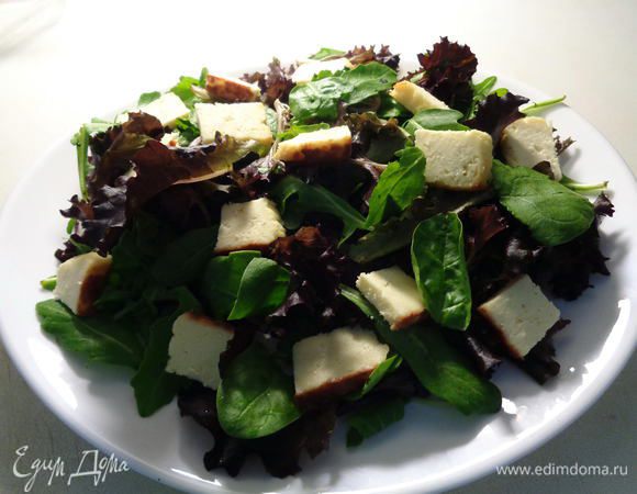 Порезать жареный сыр на небольшие кусочки и выложить его поверх салата.
Жаренный сыр у меня покупной и приготовлен из молока, яйца, закваски и соли. Обжарен со всех сторон. Очень вкусный сыр, больше похож на прессованный творог на мой взгляд. Жирность у него 20%.