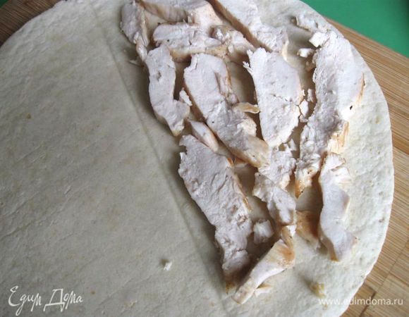 Дать курице немного остыть, нарезать пластинами, распределить кусочки курицы между двумя тортильями, положив на половинки лепешек.