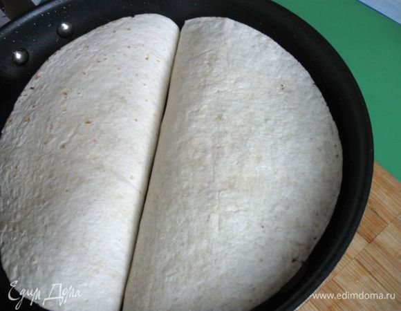Разогреть сковороду с  маслом, свернуть тортильи пополам и аккуратно положить на сковороду. Обжарить с двух сторон до румяной корочки.