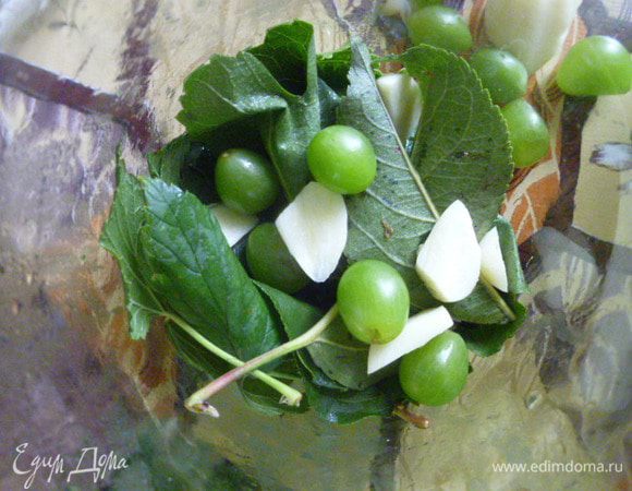 На дно стерилизованной банки кладем листья малины, черной смородины и яблони. Сверху немного чеснока и по желанию виноград. С виноградом вкуснее.