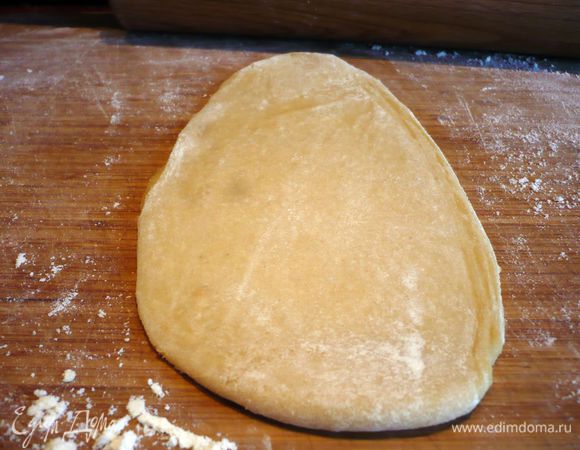 Тесто делим на 6 равных частей. Можно изначально поделить тесто при работе с ним на три части, чтобы потом разделить каждую часть на половинки. У меня две части теста были немного больше двух других, и я поделила их еще на две половинки. Каждую часть раскатываем на присыпанной мукой поверхности (тесто мы также припыляем мукой) таким образом. Сначала слегка приминаем тесто в лепешку. Теперь раскатываем в полоску. Поворачиваем тесто на 90 градусов.