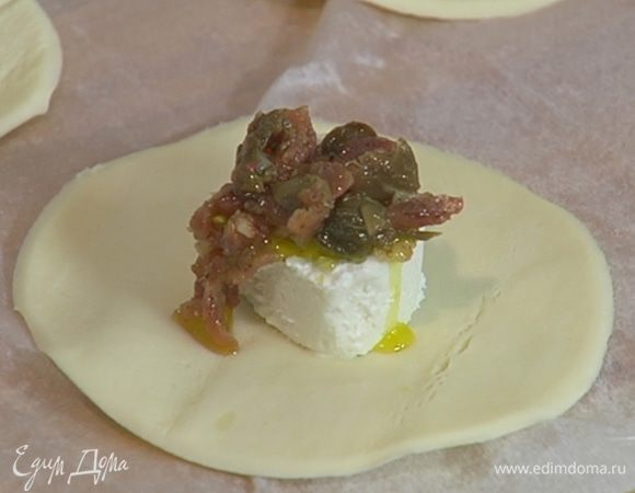 Козий сыр нарезать ломтиками, поместить на середину кружков из теста, сверху на сыр выложить по 1/4 ч. ложки начинки из каперсов и анчоусов.