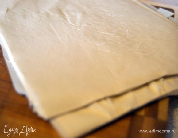 Тесто разморозить.Для начала его нужно положить в холодильник на несколько часов.Затем отделить 6 листов,нарезать из на квадратики нужного размера.Не оставлять на долго на открытом воздухе,тесто быстро сохнет и становится хрупким. Во избежании этого, накрываем влажной салфеткой.