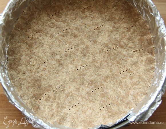 Слепить массу в тесто, выложить тесто на дно разъёмной формы с высокими бортиками, застеленную фольгой. Тесто плотно прижать ко дну формы, сформировать небольшой бортик (1,5-2 см).