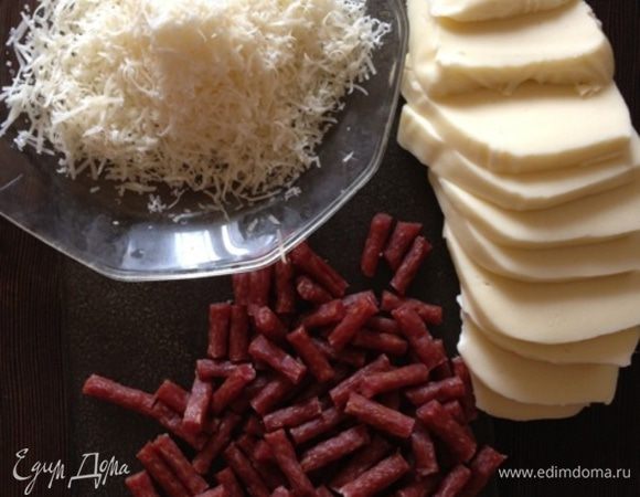 Пока подготовим начинку. Натрем на терке моцареллу, я ее резала, но лучше тереть, так она равномернее распределиться по всей поверхности основы. Порежем колбаски (у меня были тоненькие сыровяленые полусухие байсеры). Натрем пармезан. На самом деле начинка может быть любая, главное оставить сыры!!