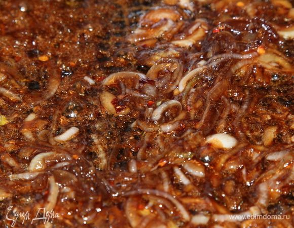 Лук нарезаем полукольцами и отправляем на сковороду с растительным маслом. Когда лук обмякнет, добавляем мелко нарезанный зубчик чеснока, перемешиваем и добавляем соевый соус, лепестки перца чили и молотый черный перец. Проготавливаем пару минут и добавляем сахар. Постоянно помешивая доводим  до образования негустой карамели. Выключаем огонь под сковородой.