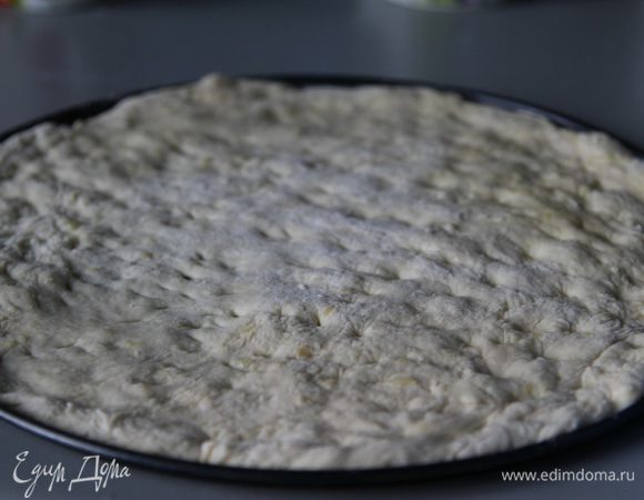 Смазать форму оливковым маслом. Тесто раскатать или растянуть по размеру формы и переложить на неё. 