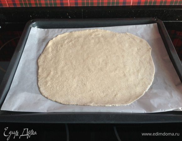 Противень застелите бумагой для выпечки и смажьте растопленным маслом. Раскатайте тесто в круг диаметром 28-30 см и положите на противень. После этого дайте тесту настояться в теплом месте в течение 45 минут.