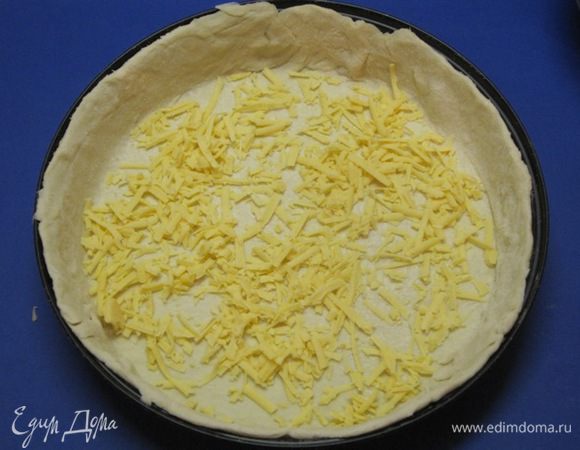 Сыр натереть на терке. Половину тертого сыра выложить на тесто.