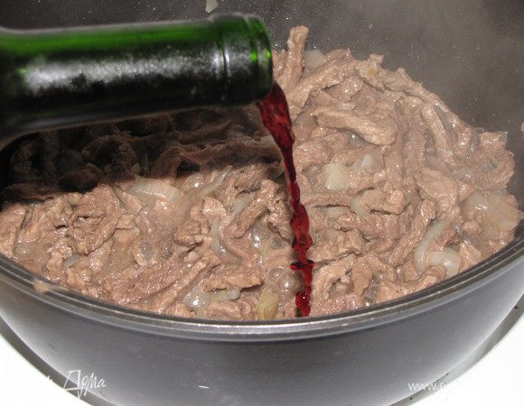 Когда мясного сока, выделившегося во время жарки, останется немного,начать понемногу добавлять вино. Убавить огонь до минимума и тушить говядину в вине 1,5 часа, все время добавляя вино по мере выкипания  жидкости и помешивая мясо.