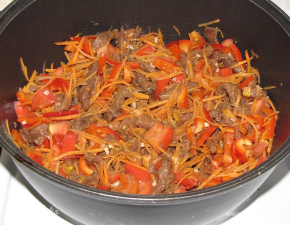 Через полтора часа добавить к мясу овощи и измельченный чеснок. Все перемешать и тушить еще пол часа.