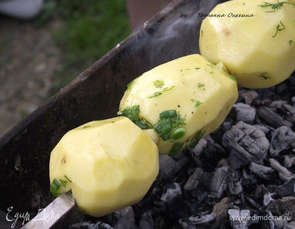Когда дрова хорошо прогорели, разбиваем угольки. На шампур аккуратно нанизываем картофель и отправляем на мангал. Если картофель не большого размера, нанизываем его целиком, если крупнее - разрезаем пополам. 