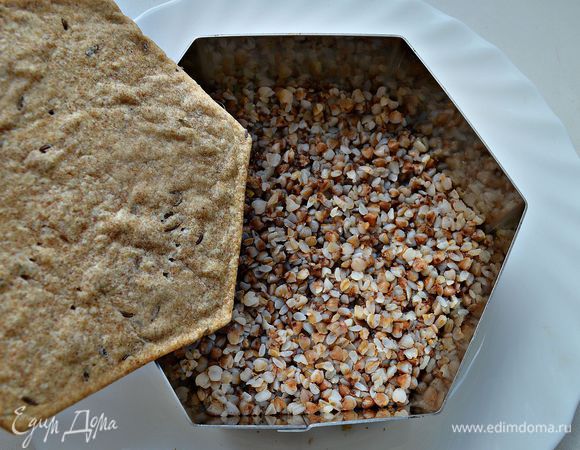 На тарелку выложить кулинарное кольцо. В кольцо слоем около 1 см выложить гречневую кашу и прижать. Сверху уложить ржаной корж.