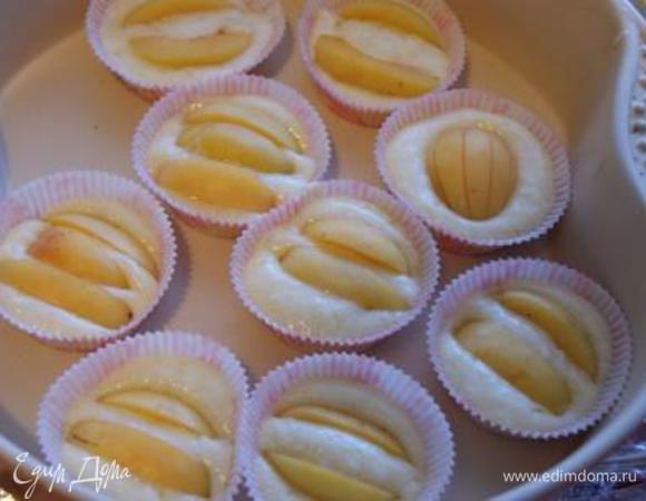 В формы для кексов выложить тесто, сверху слегка вдавить дольки абрикосов. Выпекать при 200 °C около 20 минут.