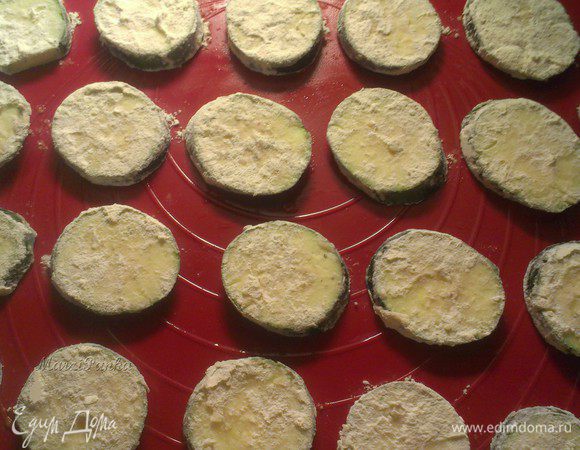 Кружочки цукини обвалять в муке и выложить на противень.

