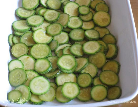 Форму для запекания смазать оливковым маслом и выложить половину цукини.