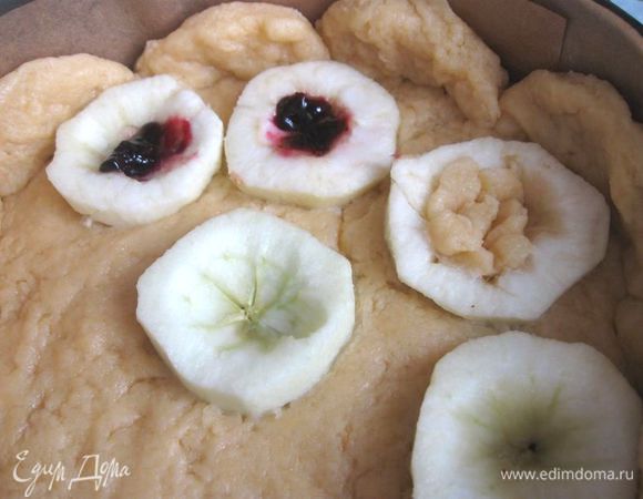 Форму для выпечки застелить пекарской бумагой ( дно и борта). Яблоки помыть, выкрутить   «хвостики», разрезать на половинки, аккуратно  (очень нежные!) небольшим острым ножом освободить от семенной части, очистить. Тесто положить на дно формы, сделать бортики. Уложить на тесто разрезами вверх яблоки, немного утопив в тесте.