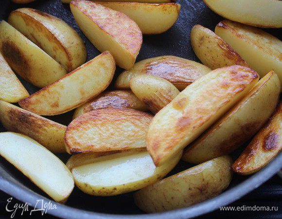 Картофель хорошо помыть, не чистить. Нарезать крупными дольками. Разогреть масло в сковороде и обжарить картофельные дольки на сильном огне до золотистой корочки. Переложить на тарелку.
