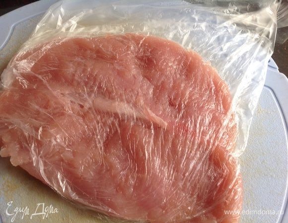 Грудку индейки накройте пищевой пленкой и отбейте.