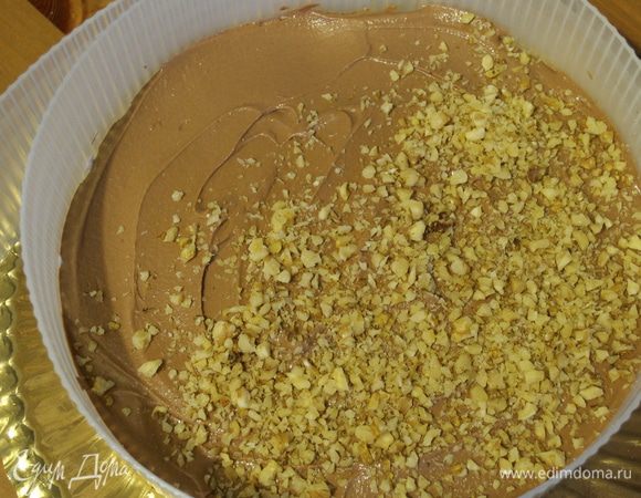 Накрыть сверху вторым коржом и выложить половину шоколадной глазури. Присыпать половиной измельченных орехов. 