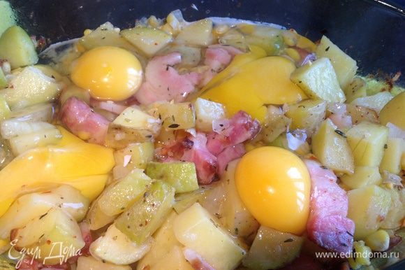 Вытащите из духовки, вбейте яйца и запекайте еще 10-15 минут.