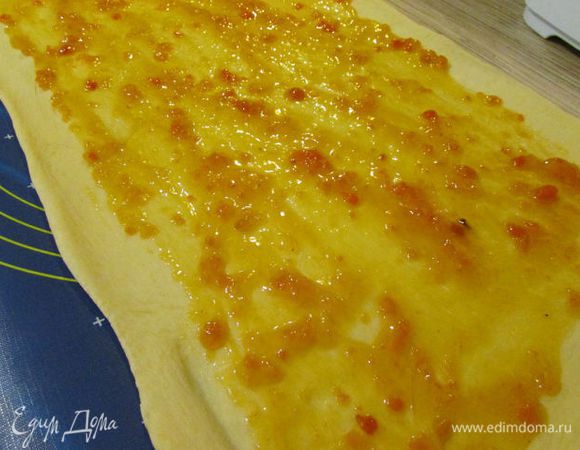 Готовое тесто раскатайте в прямоугольник 60x30 см и смажьте абрикосовым джемом, отступая на 1,5 см от края.