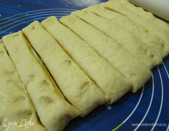 Мысленно разделите прямоугольник по длинной стороне на 3 части и сложите в трое. Получится прямоугольник 30x20 см. Защипните края и слегка прокатайте скалкой по поверхности. Разрежьте поперёк на 12 полосок.