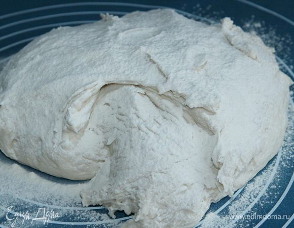 Сначала активируем дрожжи: 100 мл теплой воды+дрожжи и сахар, размешиваем и оставляем на 10 минут активироваться. Муку просеиваем, добавляем соль, щепотку витамина С, воду и активированные дрожжи. Тесто получится липким, поэтому я попросила свою хлебопечку и она любезно согласилась мне помочь. Я установила режим "Замес теста": 20 минут замеса и 1 час расстойки. Спустя это время достала тесто из контейнера хлебопечки и выложила на присыпанную мукой поверхность, сверху еще притрусила мукой.