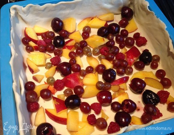 Тесто выложите в смазанную маслом форму (у меня квадратная), сделайте небольшие бортики. Сверху выложите фрукты и ягоды.