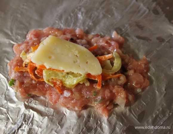 Теперь берем фольгу или на ладошке, расплющиваем немного фарша, сверху кладем сыр, обжаренные овощи, потом опять пластинку сыра. Накрываем лепешкой из фарша и аккуратно формируем котлету. (При работе с фаршем руки нужно смачивать в воде.)