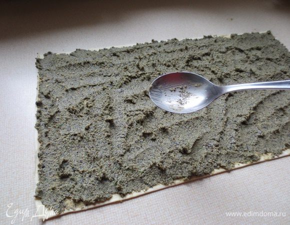 Пласт слоеного теста развернуть и смазать начинкой.