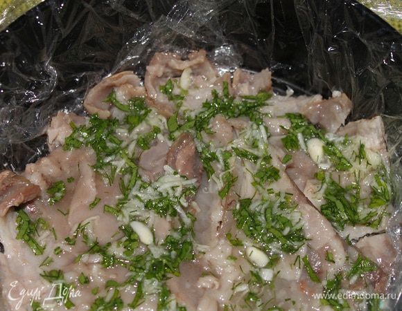 На кожу выкладываем половину начинки чеснок с зеленью. Затем кладем мясо рульки, разобранное руками на средние кусочки.